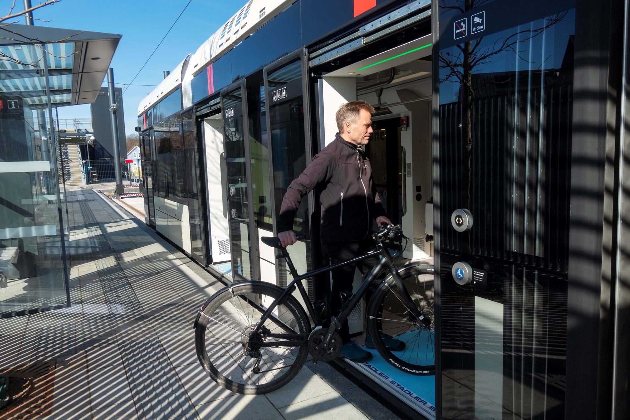 Passager med en cykel på vej ind i et letbanetog