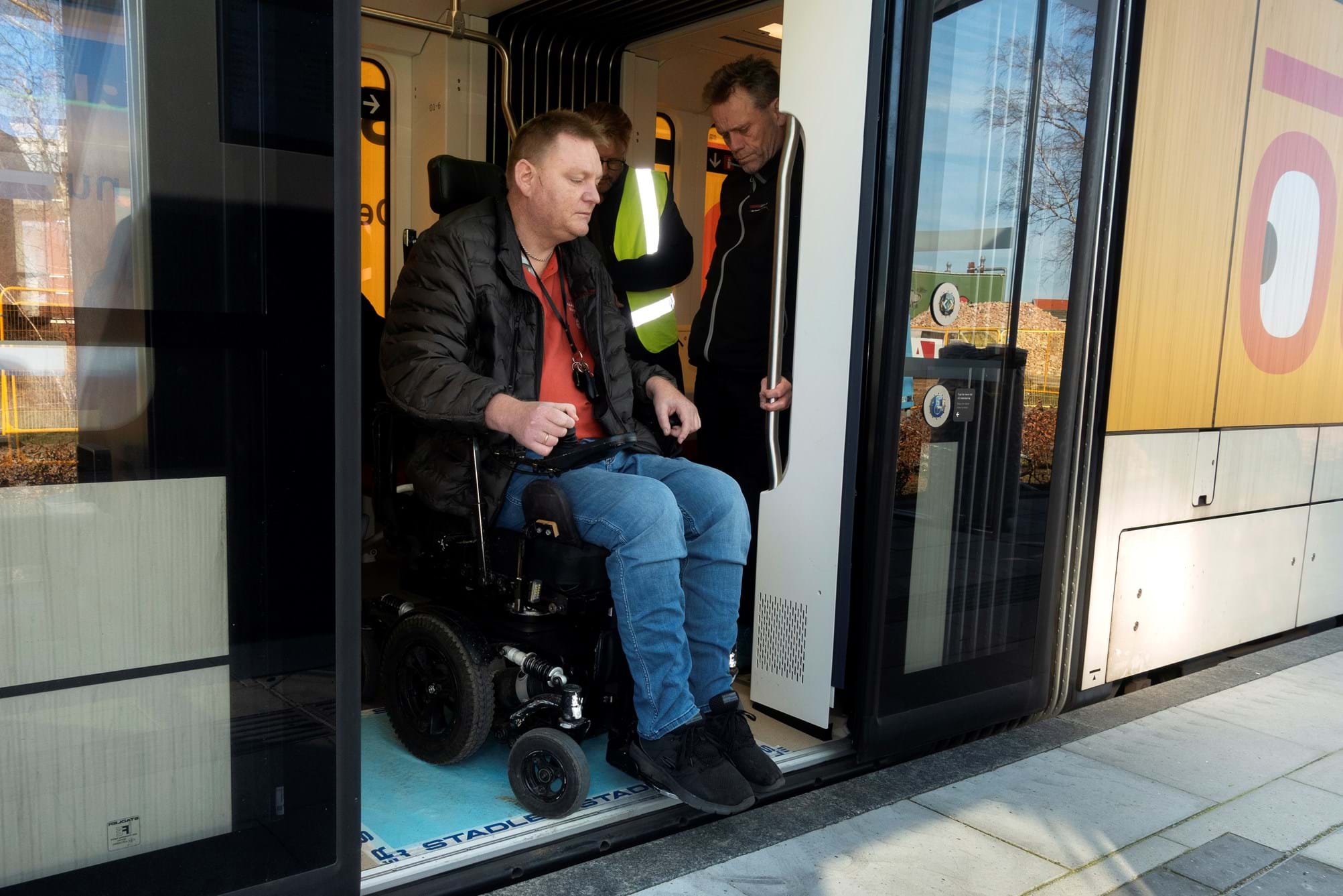 Kørestolsbruger på vej ud af letbanetoget