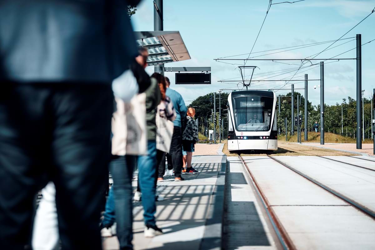 Ventede passagerer på perron og letbane i baggrunden