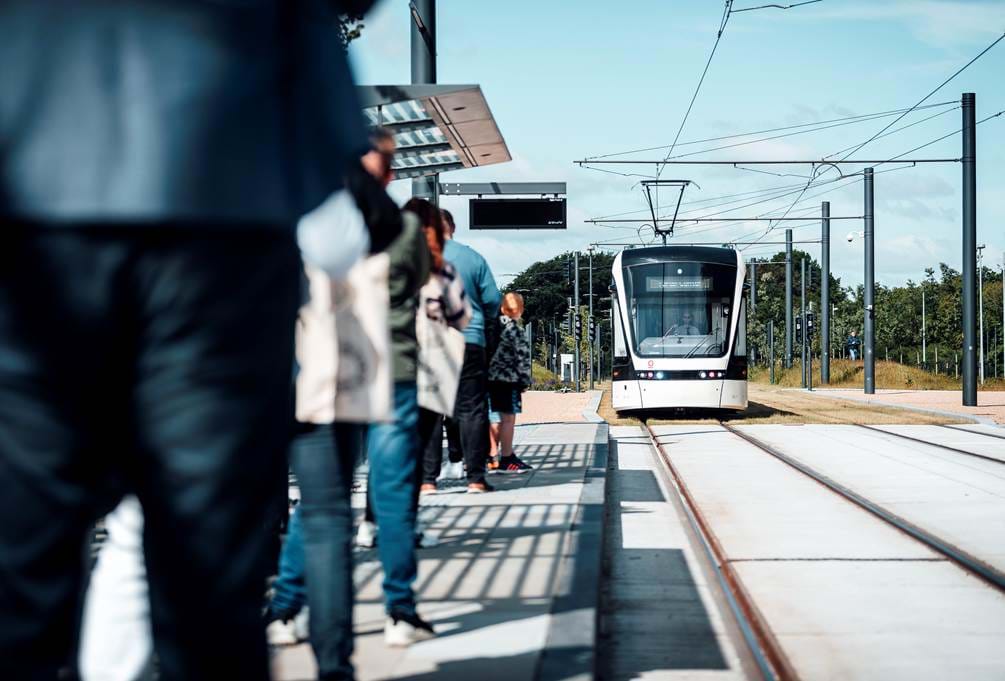 Ventede passagerer på perron og letbane i baggrunden